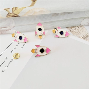 Detail of pink and white rocket enamel pins with gold finish and butterfly clutch backings