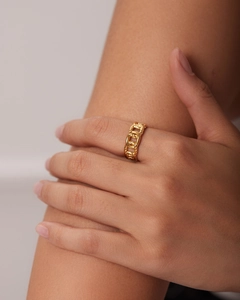 Close-up of a gold chain-link textured stainless steel ring on model finger