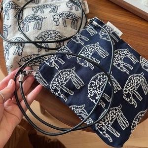 Detail of embroidered sheep pattern and metallic buckles on small canvas crossbody bags