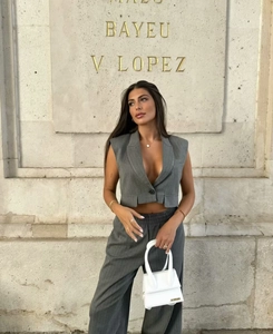 Detail of grey striped vest and wide-leg pants set with a small white handbag accessory