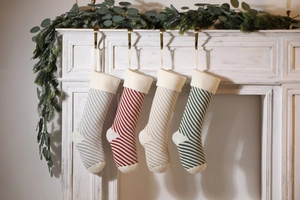 Detailed view of four striped knitted Christmas stockings hanging on a white fireplace mantle