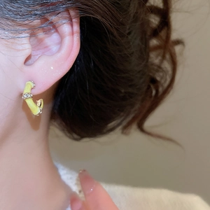 Close-up of yellow enamel C-shape earrings with rhinestones worn by a model