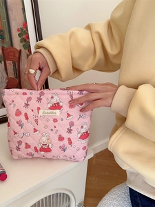 Pink quilted makeup bag with cute rabbit and flower prints held by a model