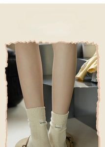 Close-up of cream cotton mid-calf socks with rib-knit cuffs and a small fabric tag detail