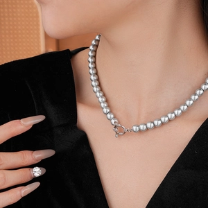Detailed view of gray pearl necklace featuring a crystal-studded silver OT clasp on model