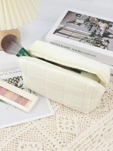 Macro view of beige quilted velvet makeup bag with metal zipper and grid pattern