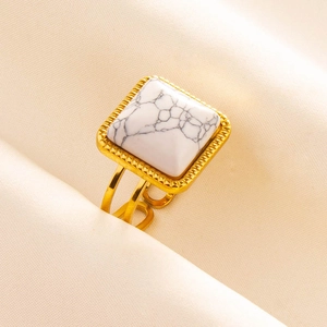 Detailed macro view of a gold-tone stainless steel ring with white marble stone inlay