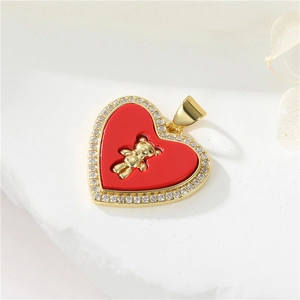 Macro detail of 14K gold plated heart pendant with red enamel, zircon stones and tiny bear