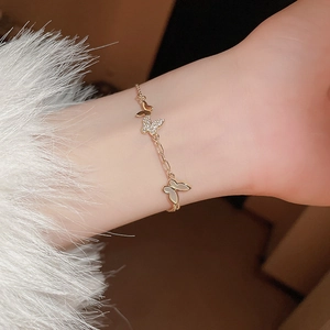 Detail view of a gold-plated butterfly bracelet with zircon and shell inserts on a model