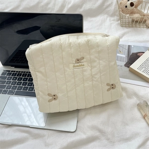 Macro view of cream quilted makeup bag with bunny embroidery and Sezakka brand label