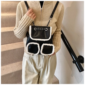 Detail of black leather backpack with white plush faux fur trim and elegant chain straps