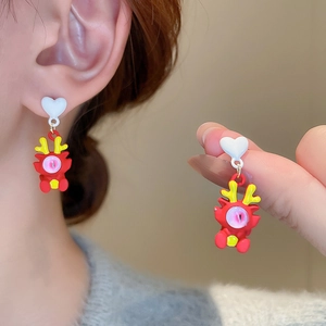 Gros plan de boucles d'oreilles dragon rouge avec clous en cœur blanc et détails colorés