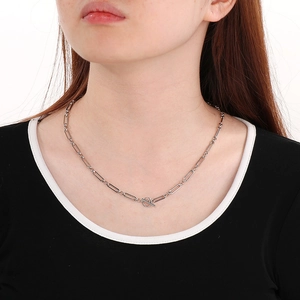 Macro shot of silver paperclip chain necklace featuring a polished toggle clasp on a model