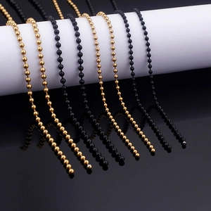 Polished stainless steel ball chain necklaces in gold and black on a white pedestal