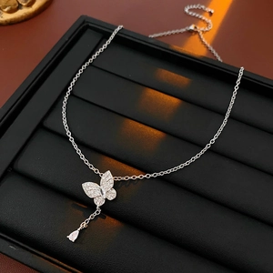 Detailed close-up of a silver butterfly pendant necklace with zircon and teardrop gemstone