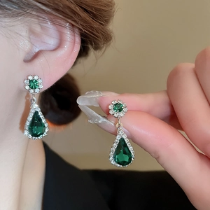 Detail of green teardrop gemstone earrings with floral crystal stud on model ear