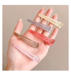 Detailed close-up of five matte translucent hair clips in diverse soft colors on a hand