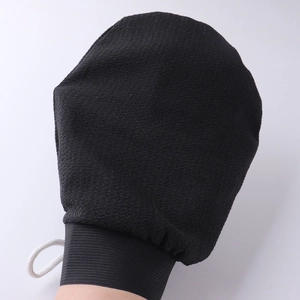 Macro view of black exfoliating bath mitt showing textured fabric and elastic cuff