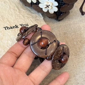 Detail view of handmade wooden and coconut shell beaded bracelet with geometric round beads