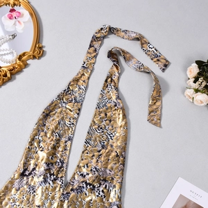 Detail of halter neck romper with gold foil animal print and metallic textures