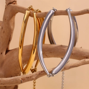 Minimalist 18K gold and silver bamboo link necklaces hanging on a natural wooden branch