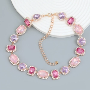 Vintage gold chain necklace with pink and purple gemstones on a white tray