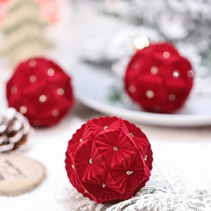 Set of three luxury red velvet Christmas balls with gold bead accents on snowy pine branches