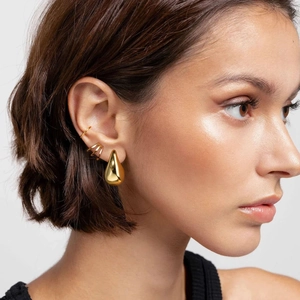 Close-up of a model wearing golden hollow teardrop earrings and sleek ear cuffs