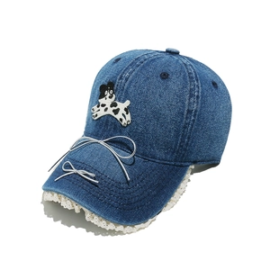 Détail d'une casquette de baseball en jean bleu avec broderie chiot et dentelle