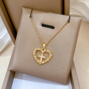 Macro shot of gold heart cross pendant with shimmering zircon and mother of pearl detail