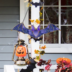 Purple marbled glass bat pendant with gold trim hanging on a spooky Halloween porch