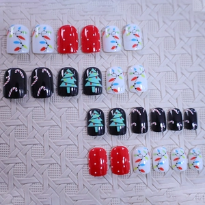 Short Christmas press-on nails featuring festive cartoon trees, lights, and polka dot designs