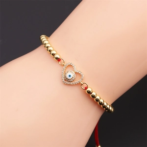 Détail d'un bracelet œil protecteur en cœur avec perles dorées et zircons brillants
