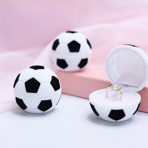 Black and white soccer-shaped velvet ring box with soft white interior on pink silk fabric