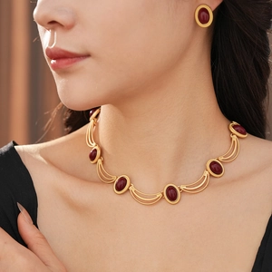 Vintage style gold necklace and oval ruby earrings set shown on a model with elegant detail