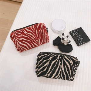Detail of zebra pattern corduroy cosmetic bags with zipper closure in red and black