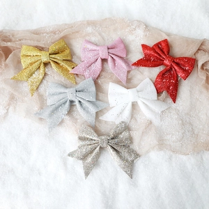 Glitter Christmas bow ornaments in six colors displayed on a snowy festive background