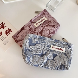 Detail of 3D embossed floral patterns and metal zipper on textured cosmetic bags