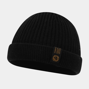 Gros plan d'un bonnet en maille côtelée noire avec étiquette logo lion jaune