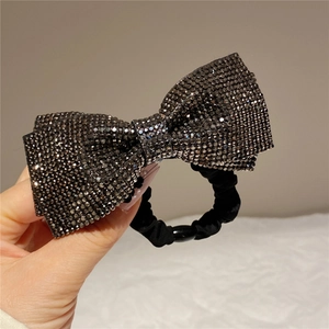 Macro view of large rhinestone bow hair tie with dark crystals and elastic black band