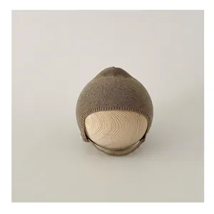 Close-up of knit baby bonnet with ear flaps and chin straps on a wooden model