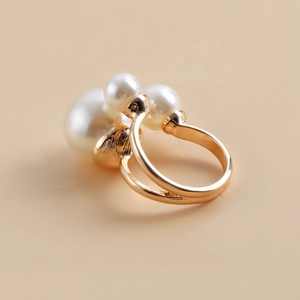 Detail view of double-layered gold ring featuring three polished white pearls on metal base