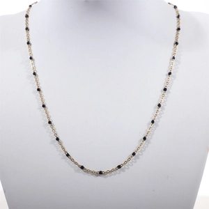 Detail view of a gold-plated stainless steel bead chain with black enamel beads on a model