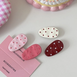 Detail of four handmade polka dot hair clips with polished resin finish and oval shape