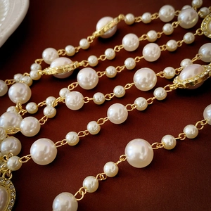 Detail showing multi-layer pearl necklace with gold chain and rhinestone oval pendant