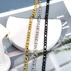 Vertical display of gold, silver, and black Figaro cuban link necklaces on a stone stand