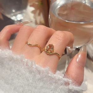 Macro view of 18k gold plated wavy rings set with amber zircon on female hand