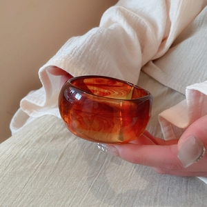 Detail of amber resin bangle with marble texture on minimalist linen background