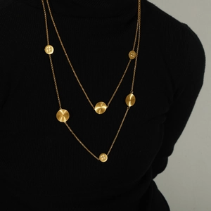 Elegant double-layered gold necklace with textured diamond-set circular pendants on model