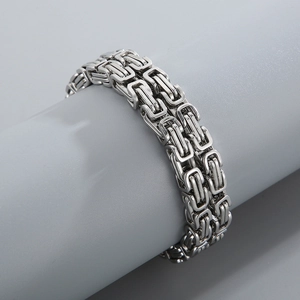 Detailed view of silver Byzantine steel bracelet wrapped on a gray display stand